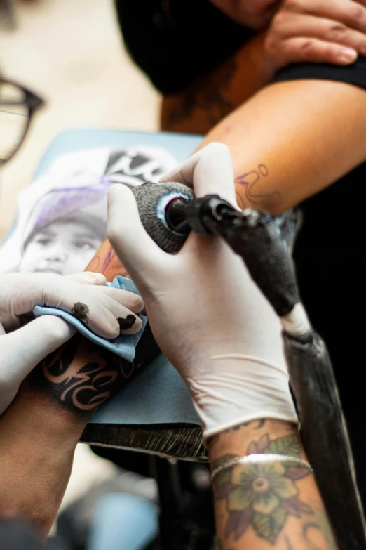 hands working on a tattoo on a person