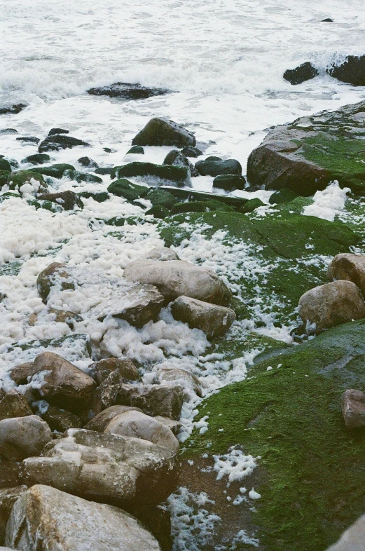 rocks with a bunch of snow covered them sitting on the edge of the water