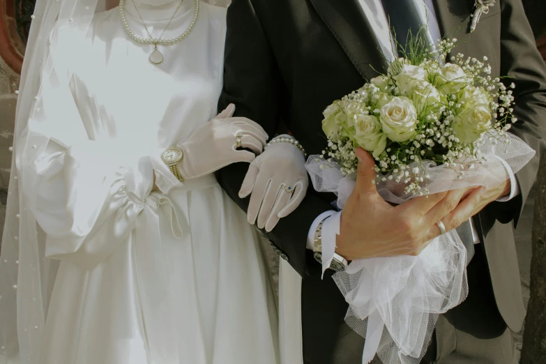 a man wearing a suit and a woman in a white wedding dress holding a bouquet