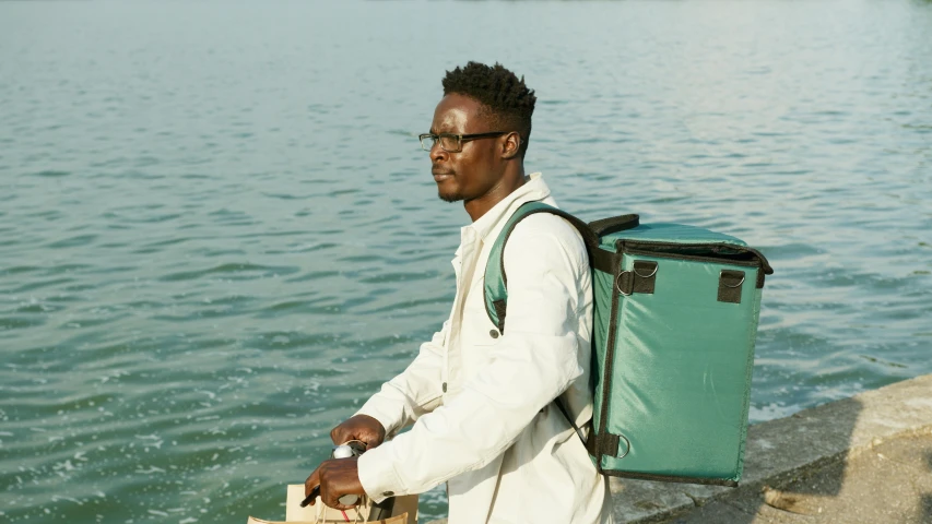 a man is standing by the water holding his luggage