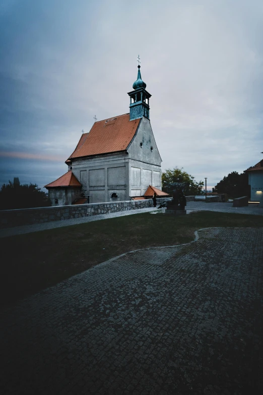 an old church with its tower and steeple is pictured on a cloudy evening