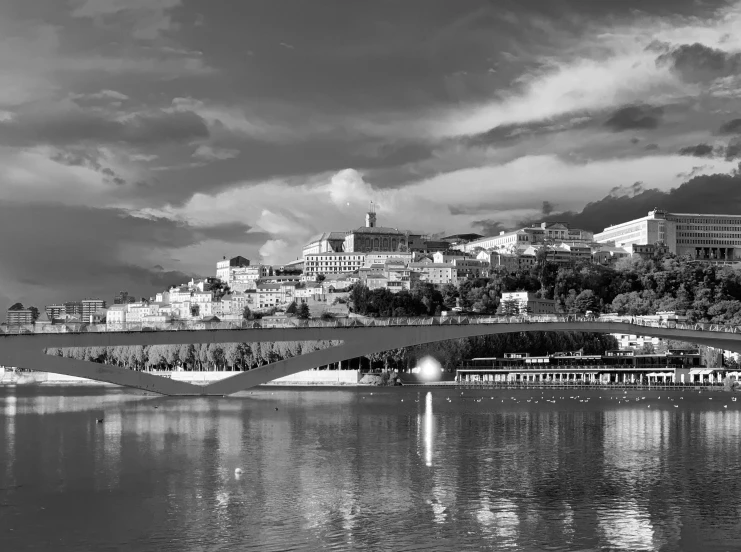 a bridge over water with a building on the hill behind it