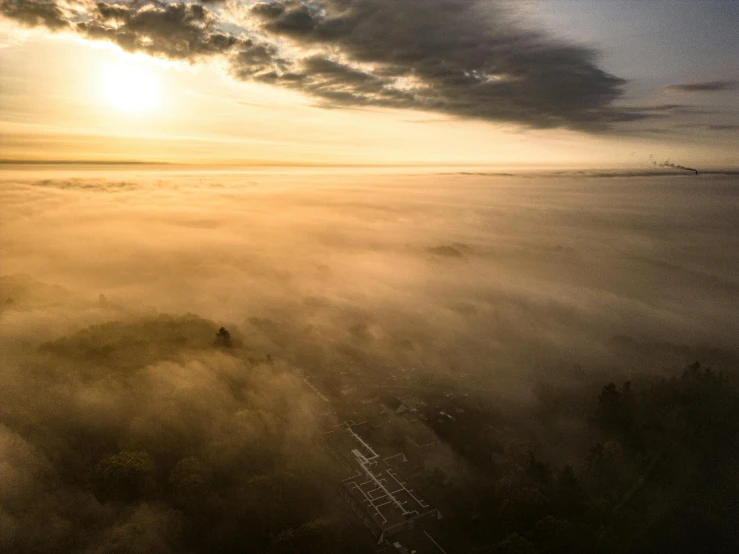 the sun is above a valley covered in fog