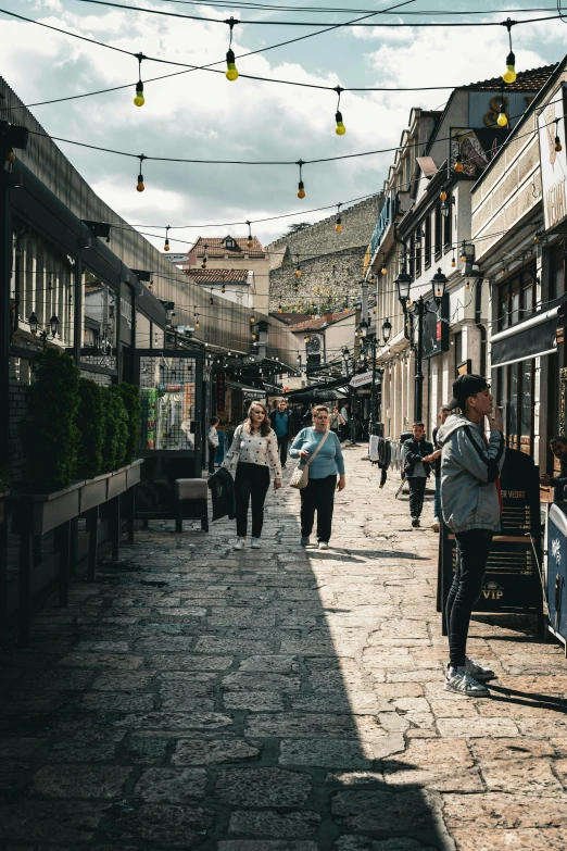 people walk on the cobblestone sidewalk along the street