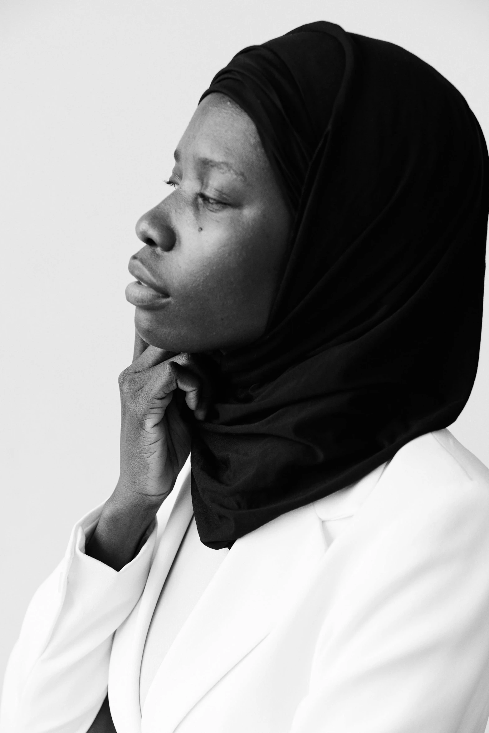 a woman wearing a black headscarf while holding her head up