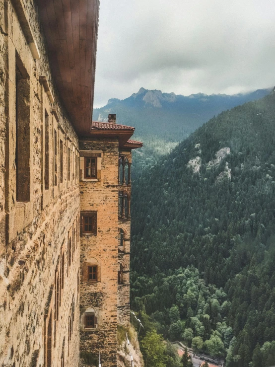 an old brick building next to a tree lined mountain range