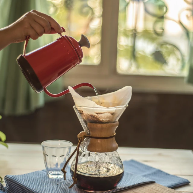 a person pours tea into a glass pitcher on top of a blue napkin