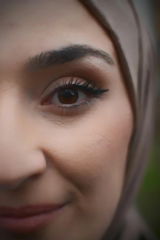 a woman wearing a hijab with long eyelashes looks straight ahead