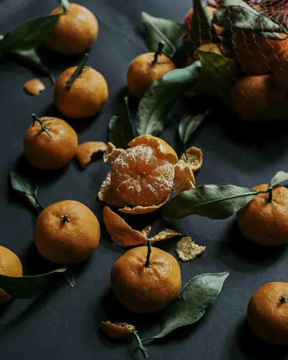 group of peeled oranges and leaves on black background