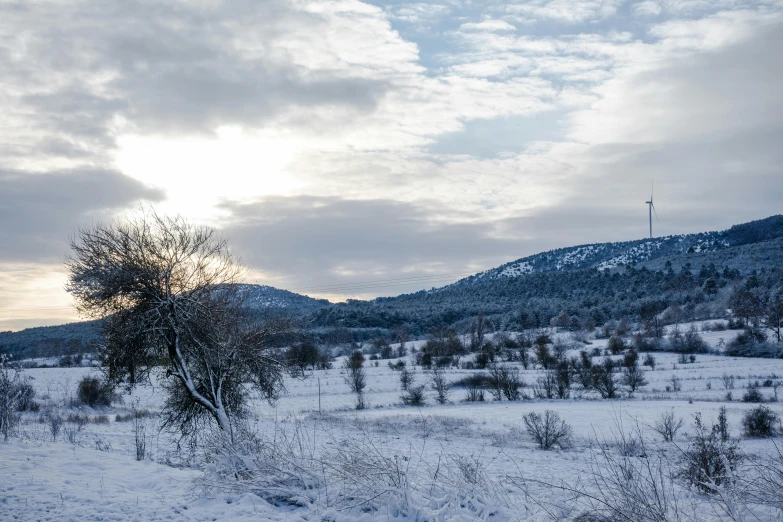 the sun shines through clouds on a snow covered hillside