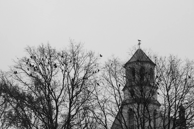 an old building with clock tower and spire next to trees