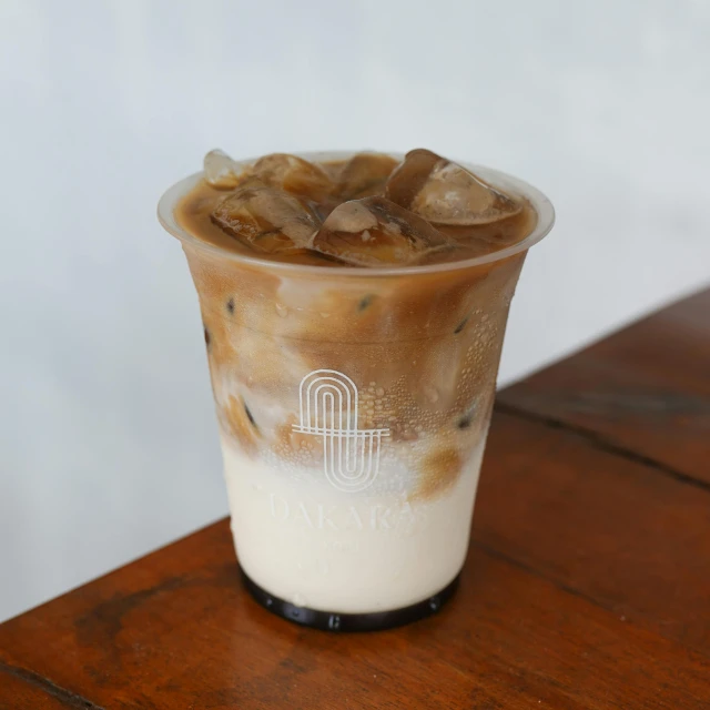 an iced beverage in a tall glass sitting on a wooden table