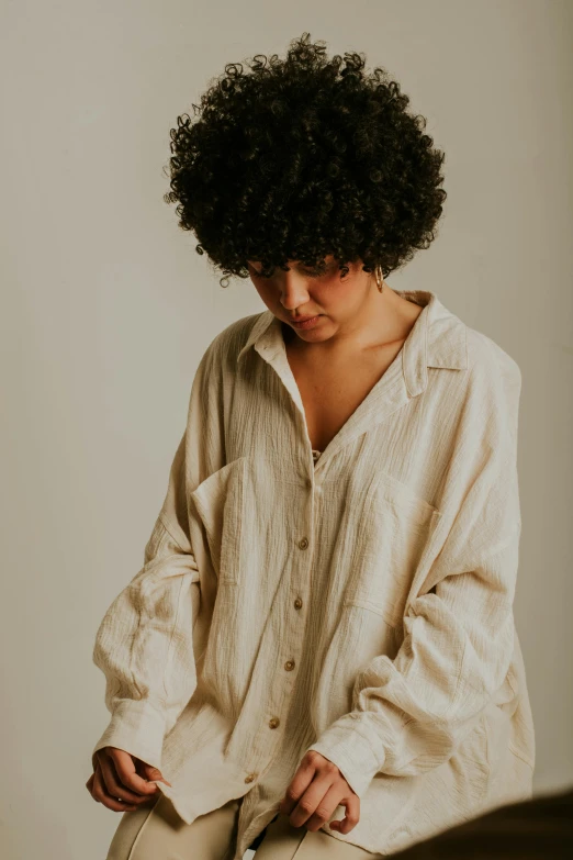 a woman in a white shirt and tan pants sits with her hands under her chest