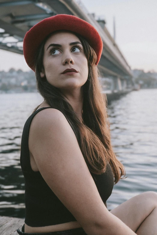 a girl sitting on a wooden plank wearing a red hat