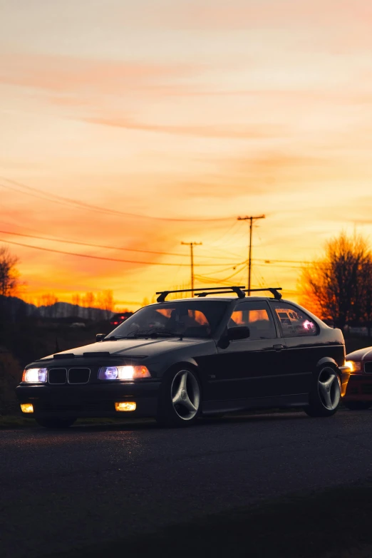 a black car parked next to other cars at dusk