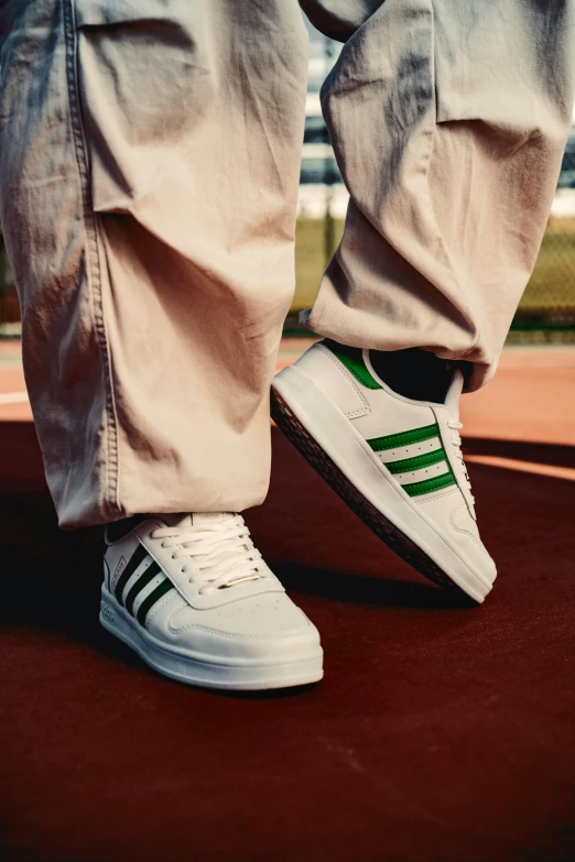 a white tennis shoe with green stripes on it's soles