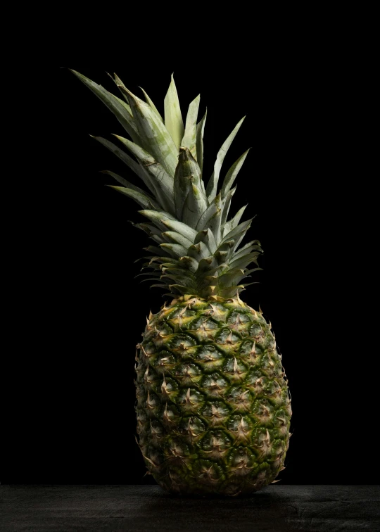 a fresh pineapple sits in front of a dark background