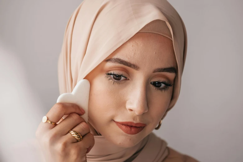 a woman in a hijab holds a white device