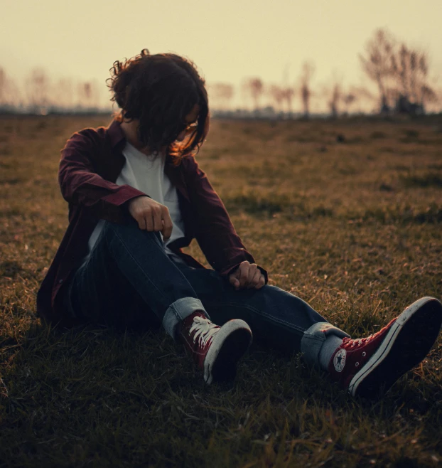 a man sitting in the grass next to a forest