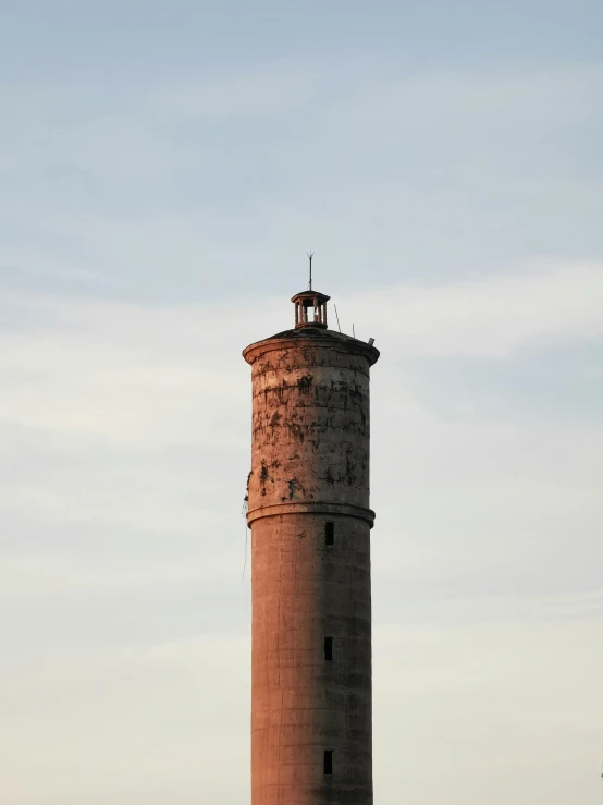 a red brick lighthouse in the background, with a large body of water in front of it
