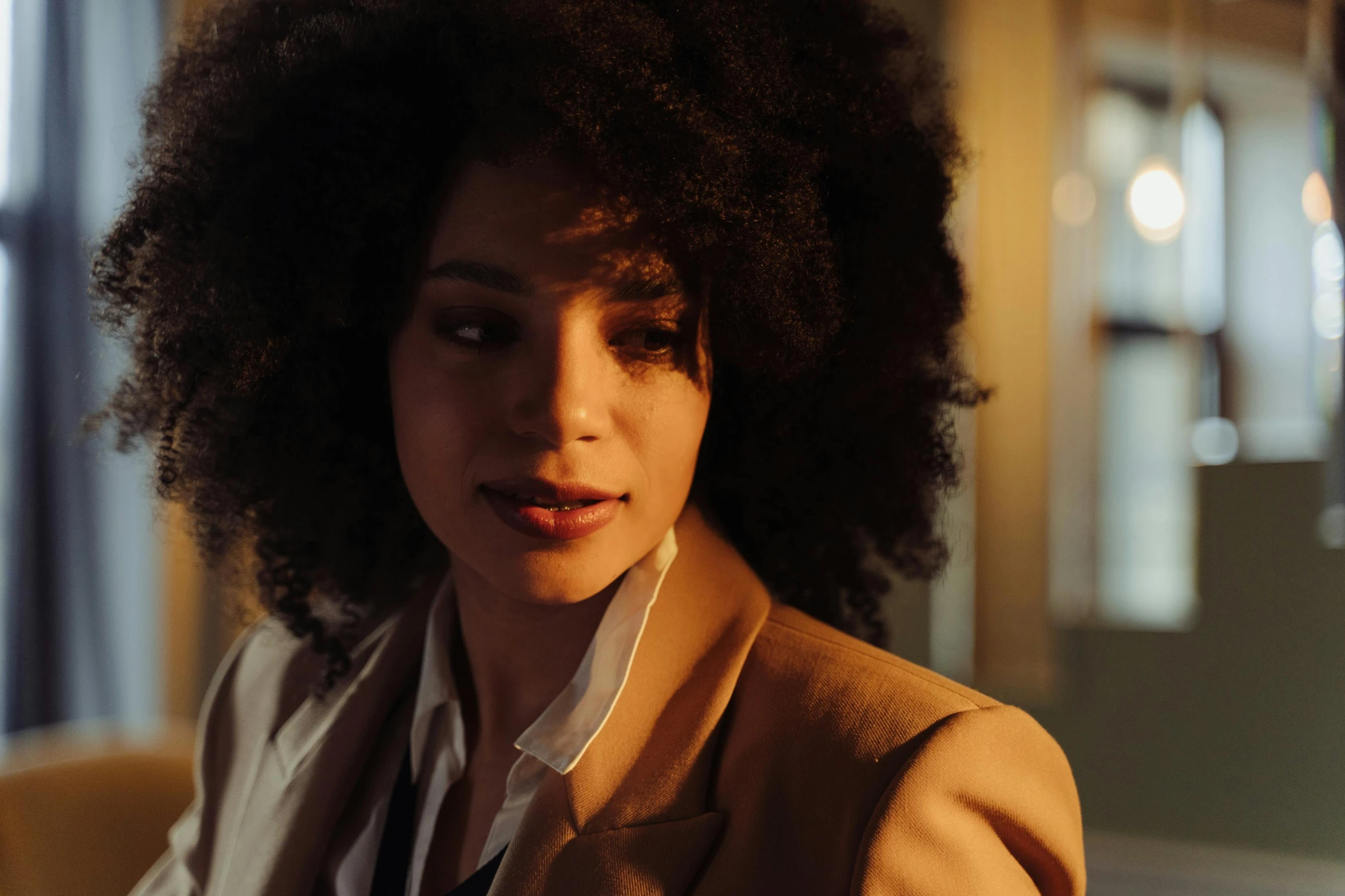 a woman with a curly afro looks away from the camera