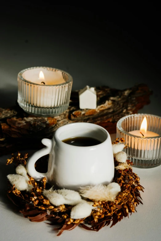 there is a candle sitting on a pile of nches next to a mug