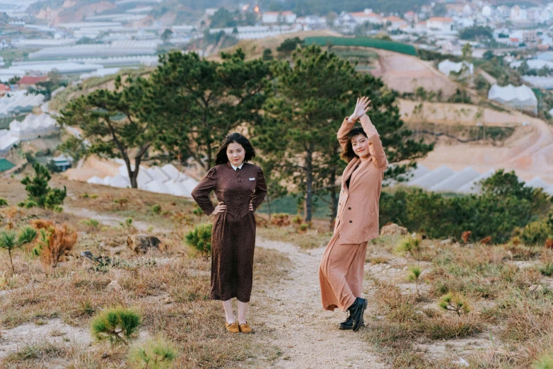 two women are standing on a hill, their arms spread