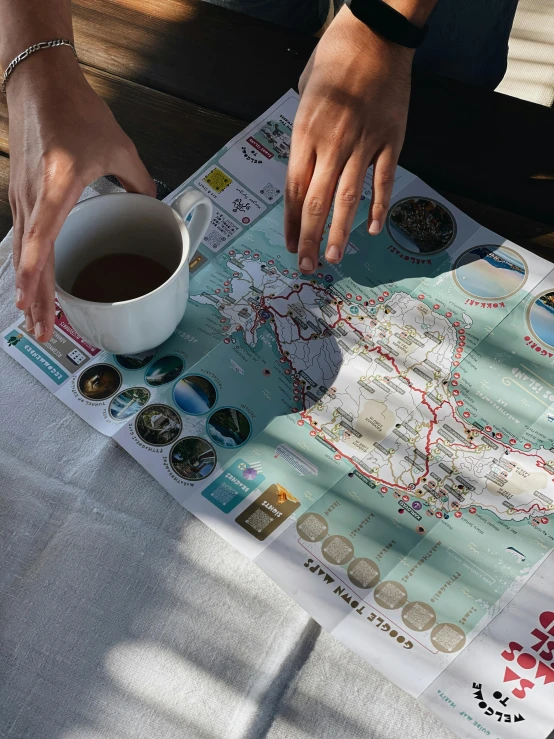 someone reaching out on a map with a cup of tea