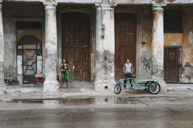 people standing near two large wooden doors and one is pulling a cart