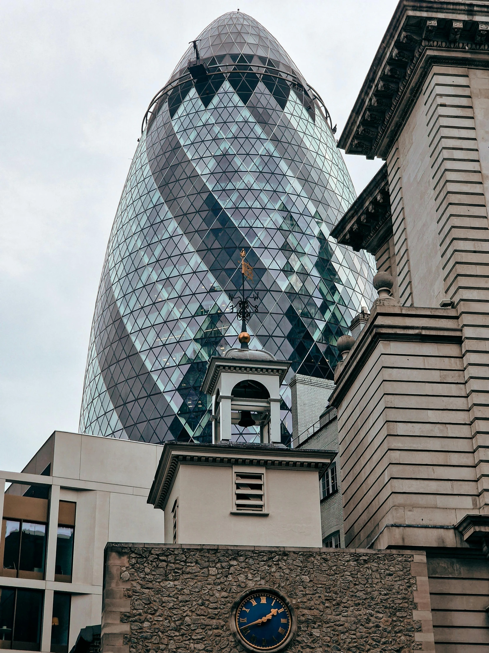 a clock on the side of a building in front of an upward glass dome