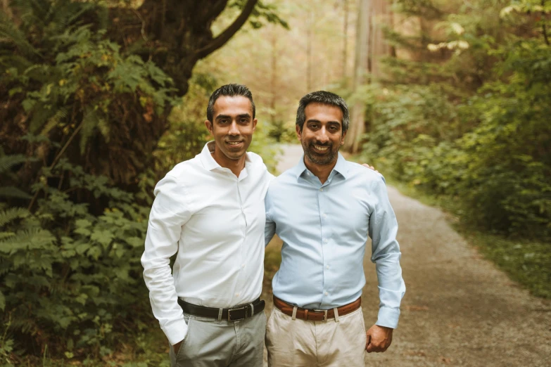 two men standing in the woods smiling for the camera