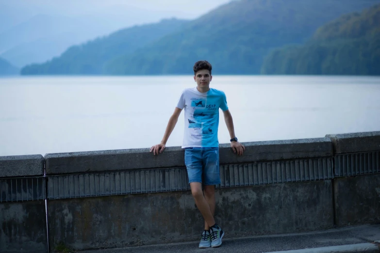 man wearing blue shorts with black and white shirt next to water