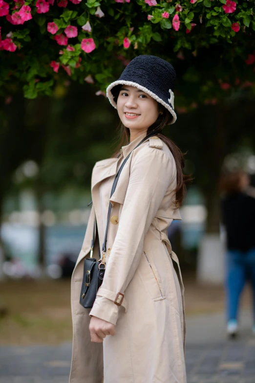 a woman in a trench coat holding her hand under her waist