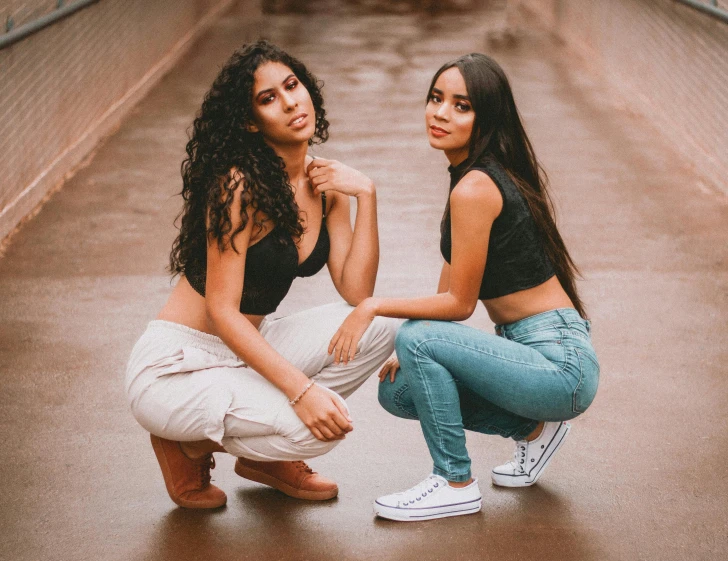 two girls are sitting on a bridge one is crouched down