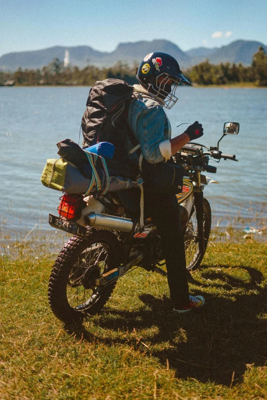 the man is riding his motorcycle by the water