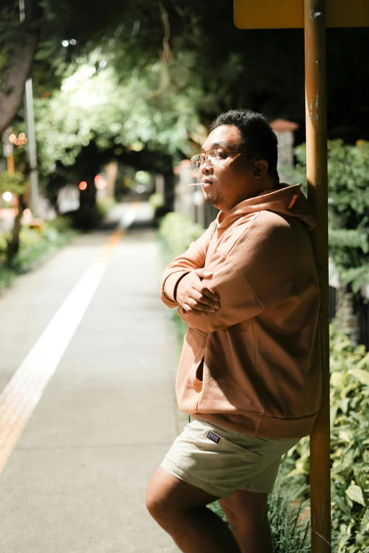 a man leaning against a post next to a road