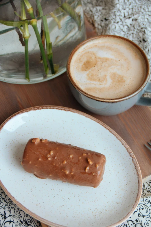 there is a chocolate pastry on a white plate and a cup of coffee