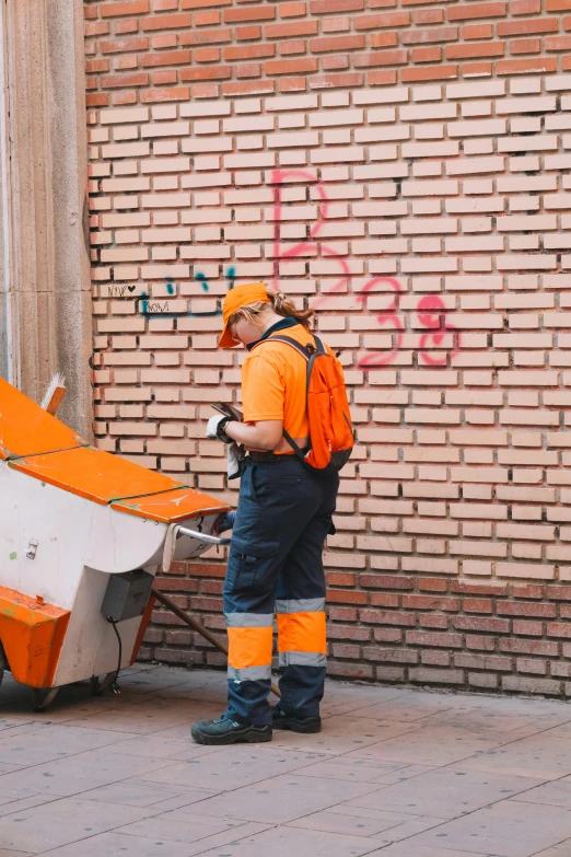 man with safety equipment and brick wall holding a piece of equipment