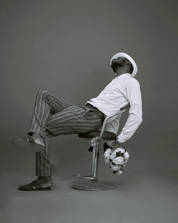 a man in a white shirt and a hat sitting on a chair