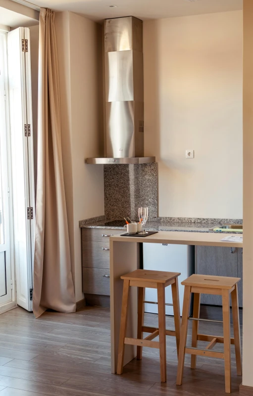 a kitchen with two stools on top of a wooden floor