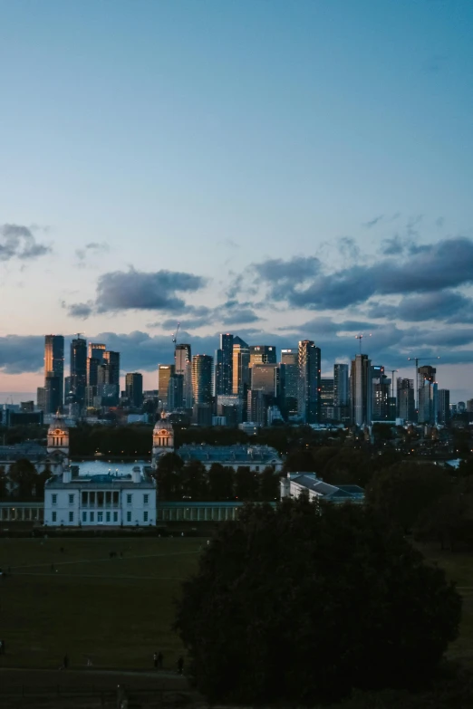 a city skyline is silhouetted against the clouds at dusk