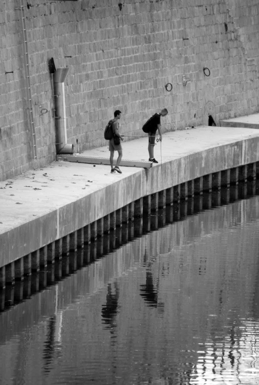 two people walk by a body of water with an umbrella on
