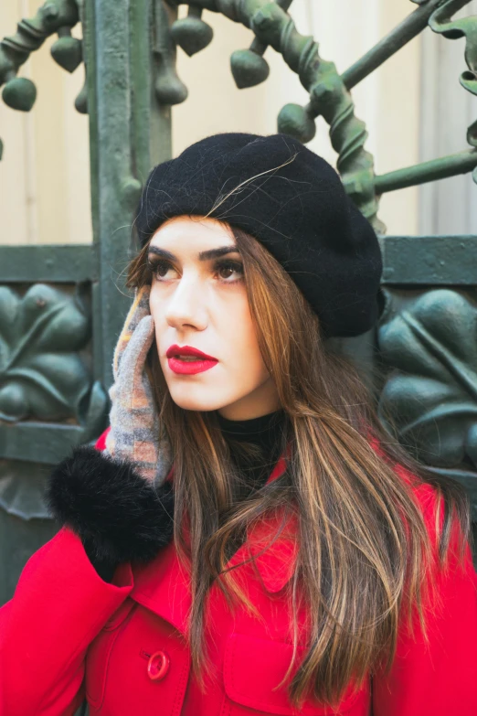 a woman wearing a red coat, black hat and red lipstick