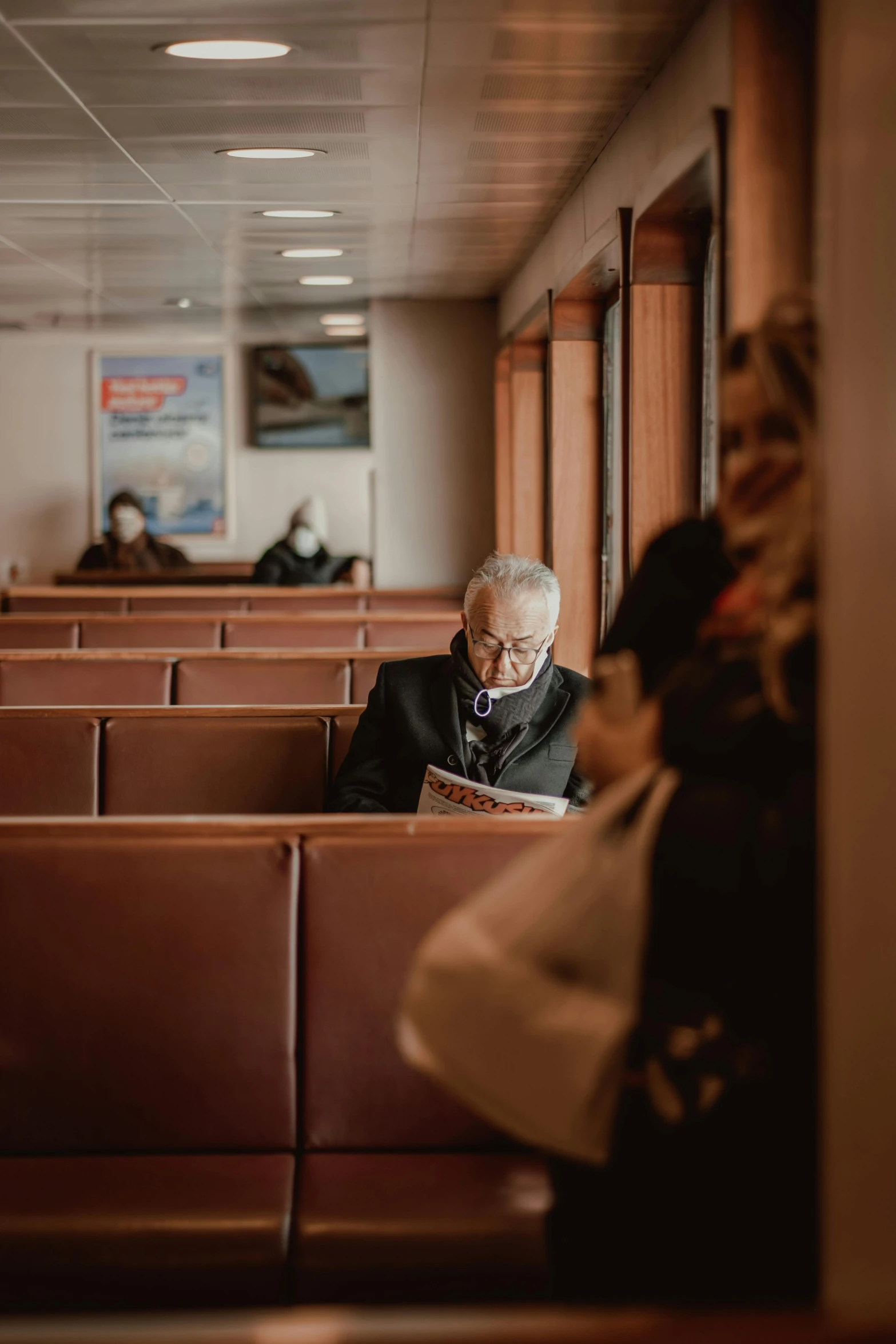 an old man sitting in a wooden booth on the train