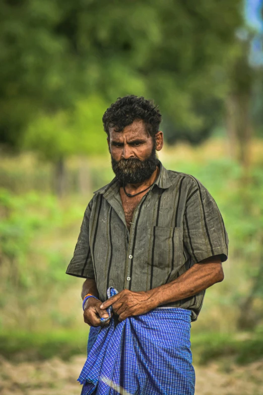 a man is walking on the dirt road with a blue bag