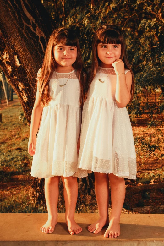 two little girls posing for the camera with one of them holding her hands to her ear