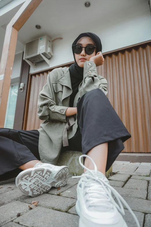 a woman is sitting on the ground wearing sneakers