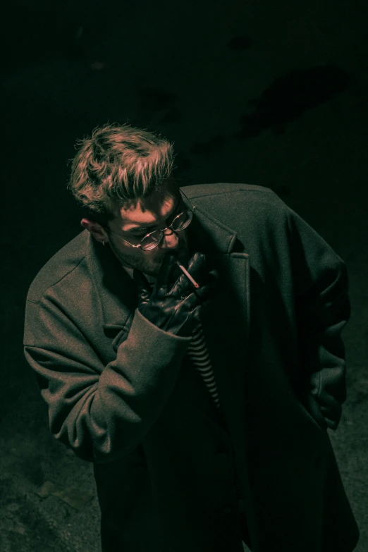 a man with glasses and a coat is talking on the phone