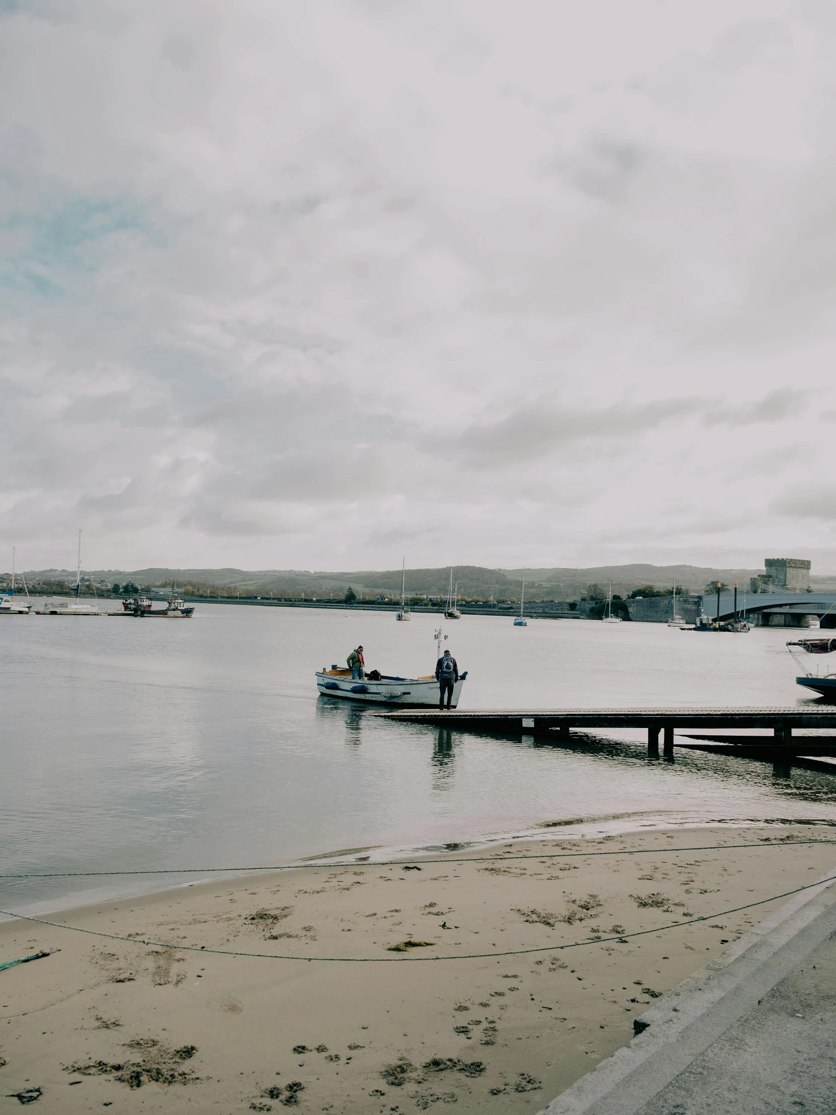 a man standing on the water next to a pier with fishing boats docked in it