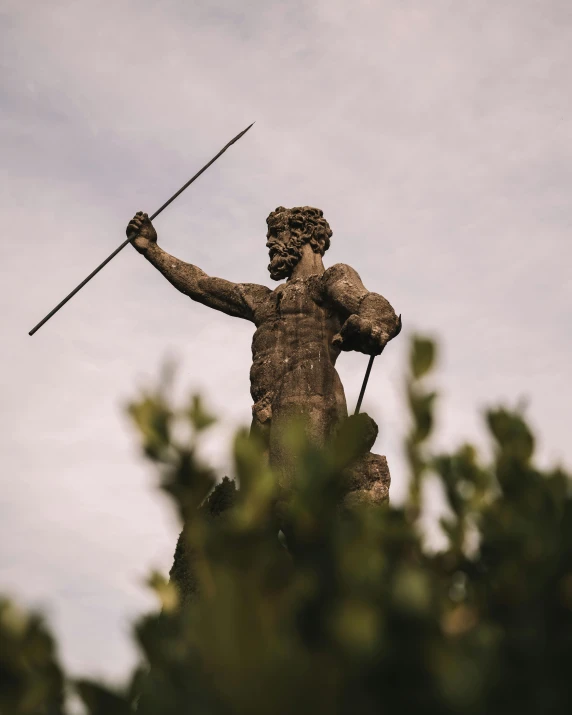 a statue is posed to hold two canes above a forest